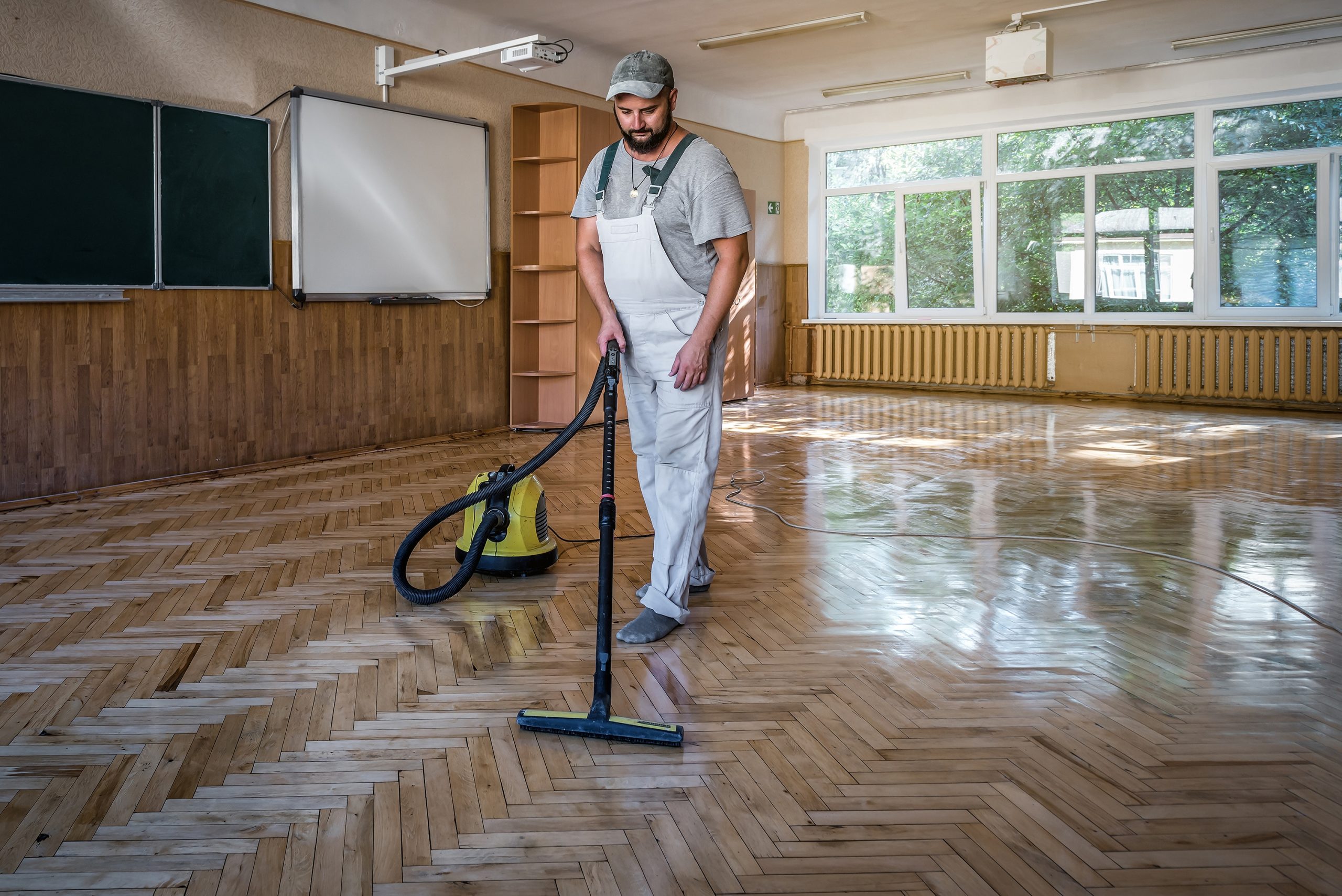 School Floor Buffing in Clapham on oak herringbone parquet inside a classroom, technician cleaning and perfecting a bright, safe finish.