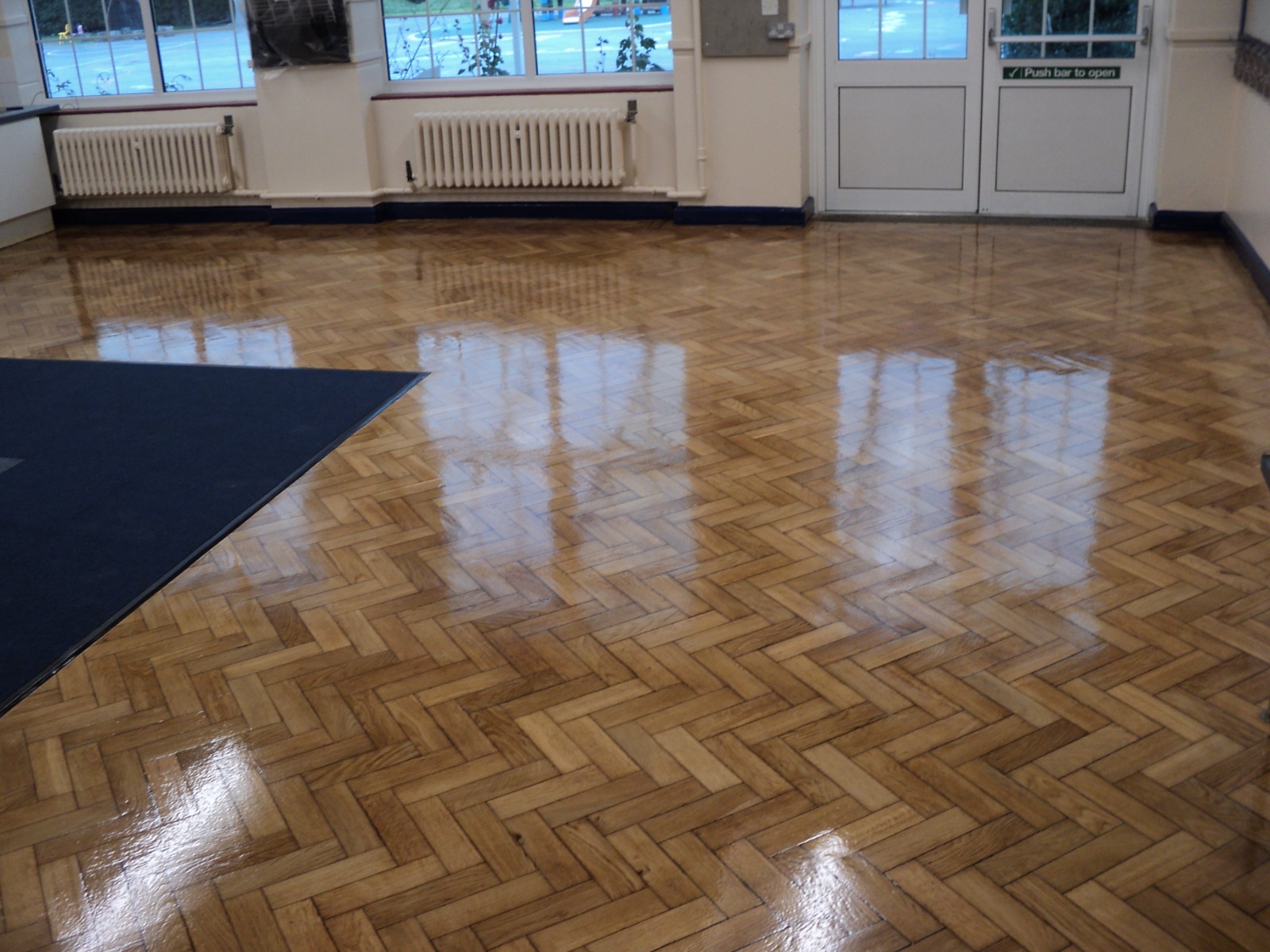 School Floor Buffing in Clapham on an oak herringbone parquet school hall, freshly buffed to a bright, even, slip-resistant sheen.