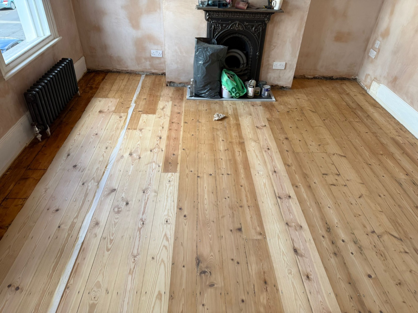 Clapham Floor Sanding on Victorian pine softwood floorboards in a Clapham living room, showing newly sanded pale boards alongside older darker sections before finishing.