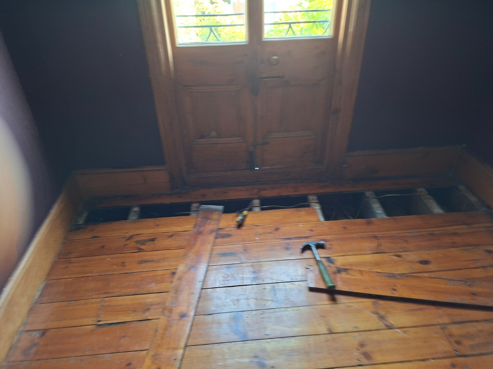 Clapham Floor Sanding and joist inspection on Victorian pine softwood floorboards in a Clapham room, with boards lifted near the doorway for subfloor repairs.