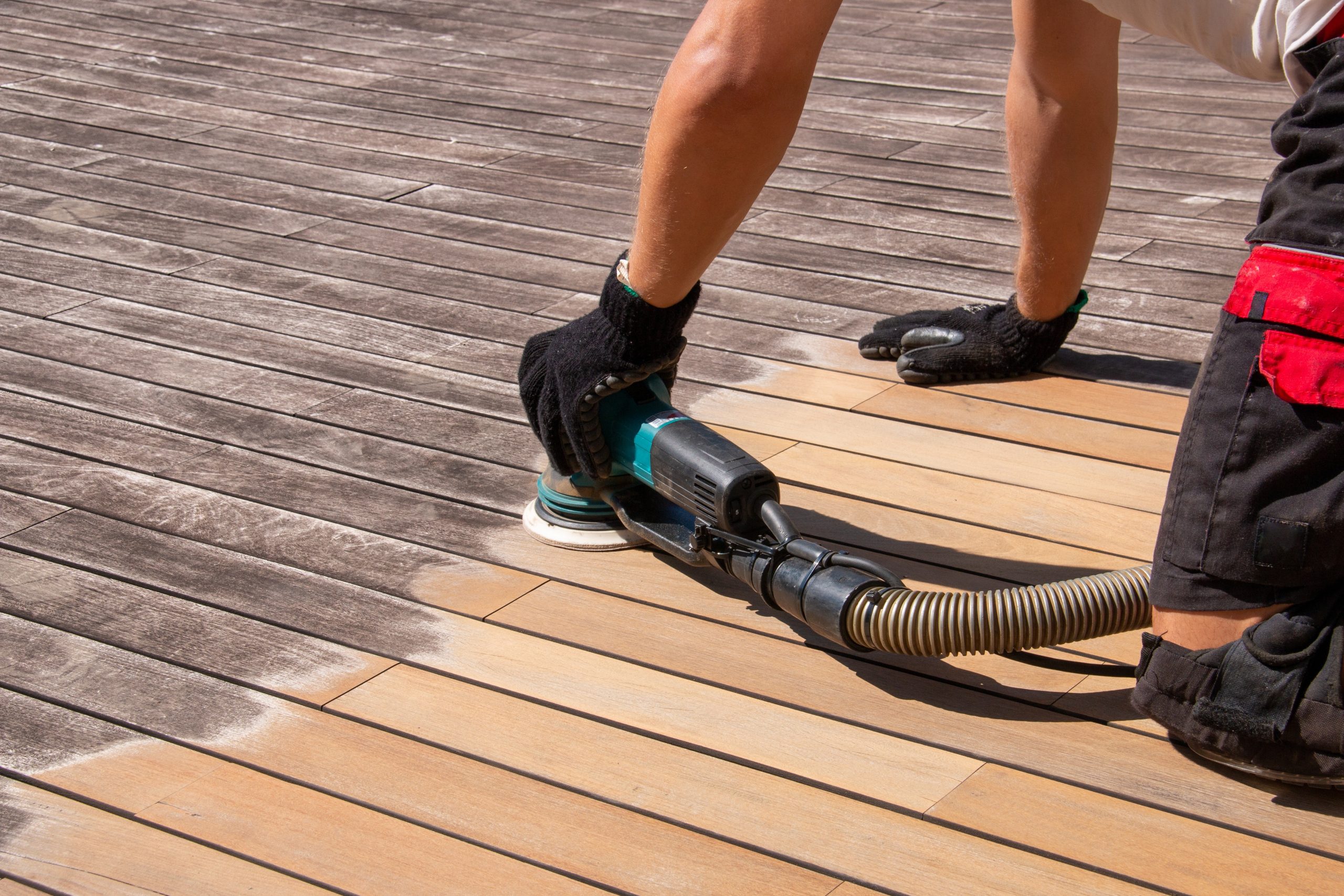 Deck Sanding and Renewal in Clapham on weathered hardwood deck boards, showing a professional sanding the outdoor timber floor to reveal clean, smooth wood.