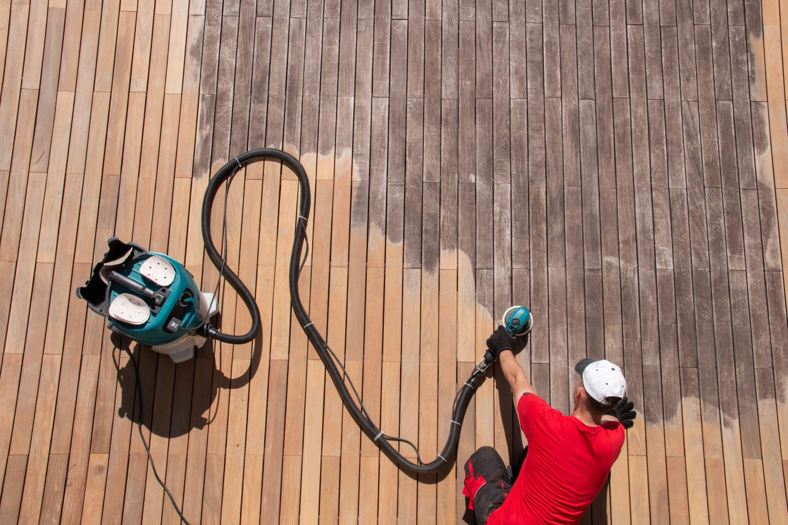 Deck Sanding and Renewal in Clapham on a weathered hardwood timber deck floor, showing a technician sanding grey boards back to fresh, smooth wood.