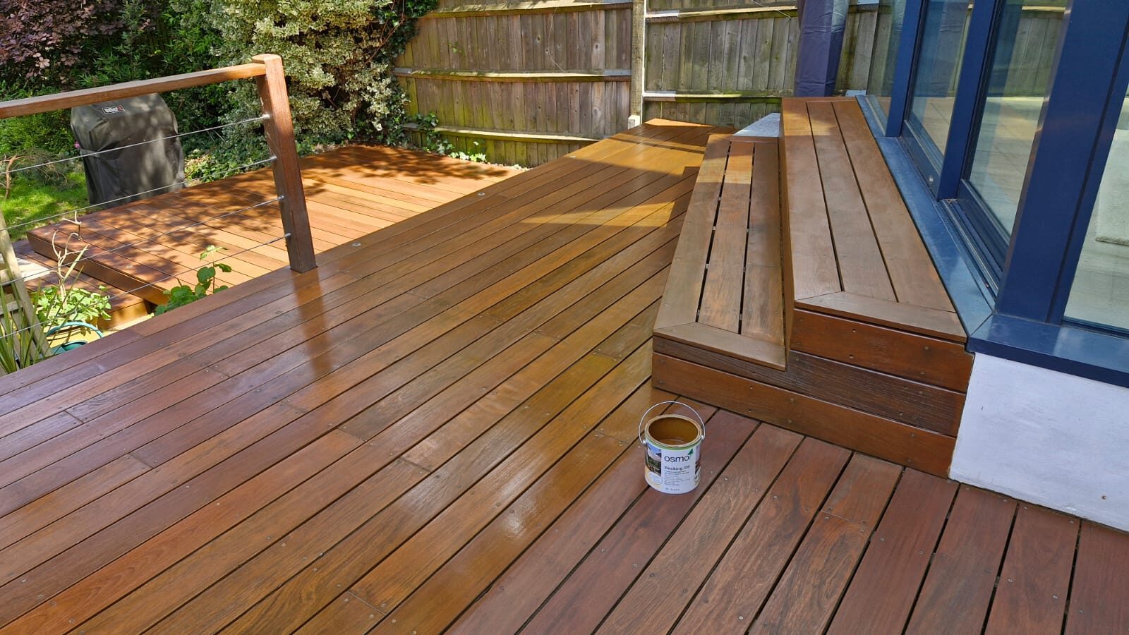 Deck Sanding and Renewal in Clapham on a split-level hardwood timber garden deck, freshly oiled for a rich, smooth finish beside patio doors.