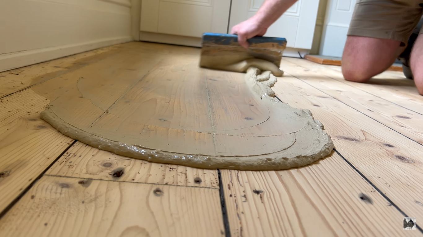 Wood Floor Sanding in Clapham with gap filling on Victorian pine softwood floorboards, as a specialist spreads resin across the sanded timber to seal gaps before finishing.