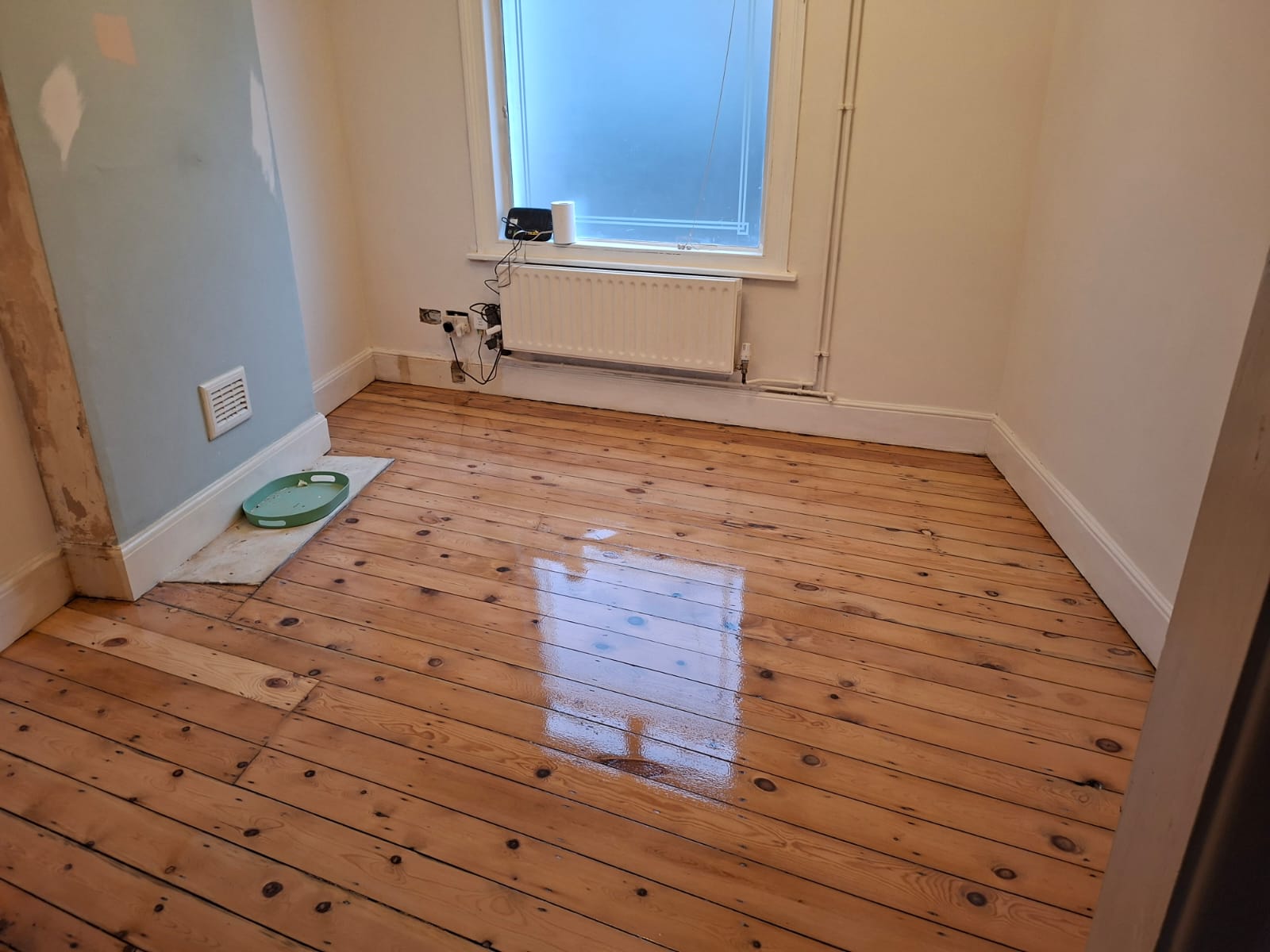 Freshly finished Wood Floor Sanding in a Clapham bedroom, showing original pine floorboards restored to a smooth, glossy, honey-coloured finish.